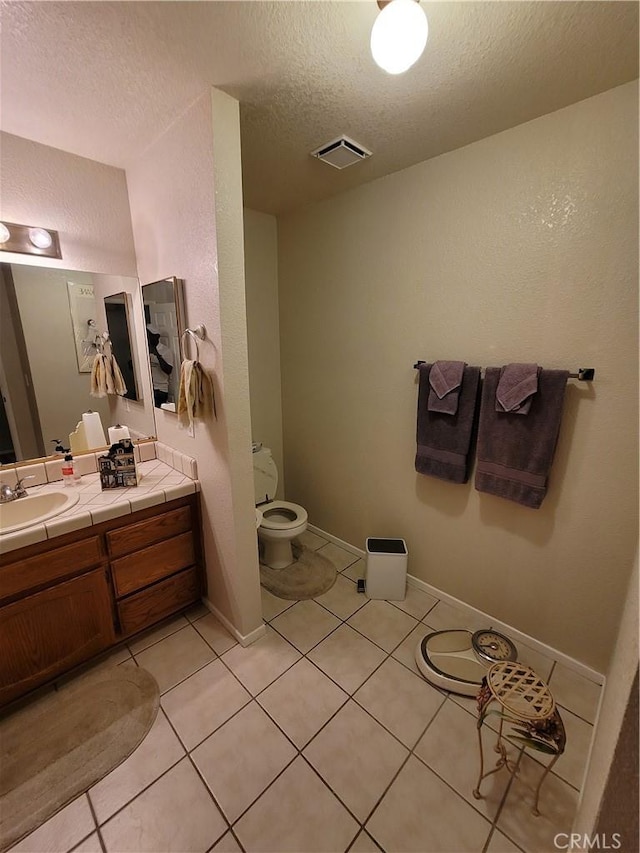 bathroom with tile patterned floors, vanity, a textured ceiling, and toilet