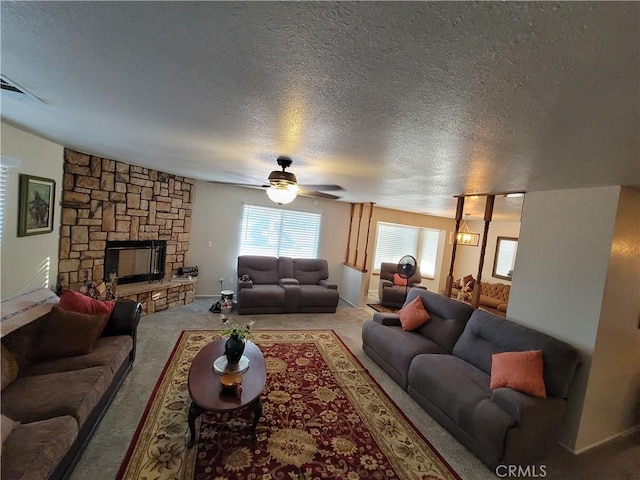 living room with carpet, ceiling fan, a fireplace, and a textured ceiling