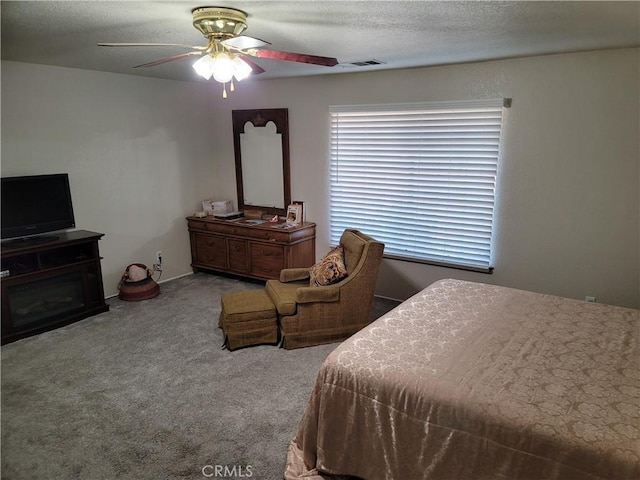 carpeted bedroom featuring ceiling fan and a textured ceiling