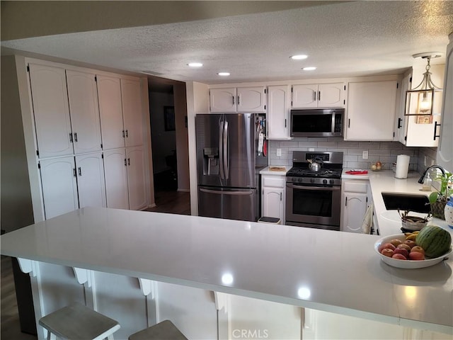 kitchen featuring a breakfast bar, backsplash, white cabinets, sink, and stainless steel appliances