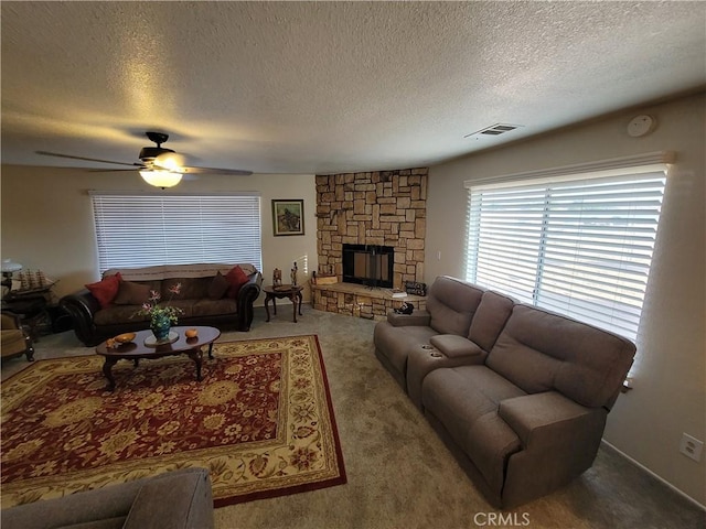 living room featuring a textured ceiling, ceiling fan, carpet floors, and a fireplace