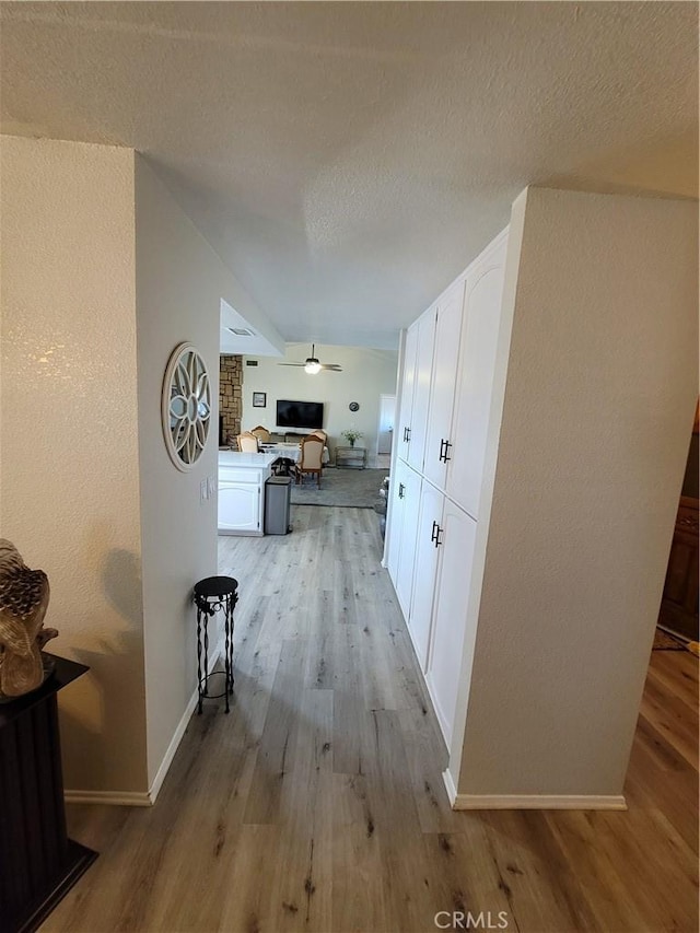 corridor featuring light wood-type flooring and a textured ceiling