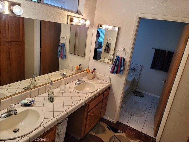 bathroom with tile patterned floors, a bathing tub, and vanity