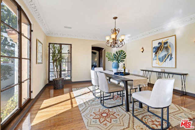 dining area with crown molding, wood-type flooring, and a chandelier