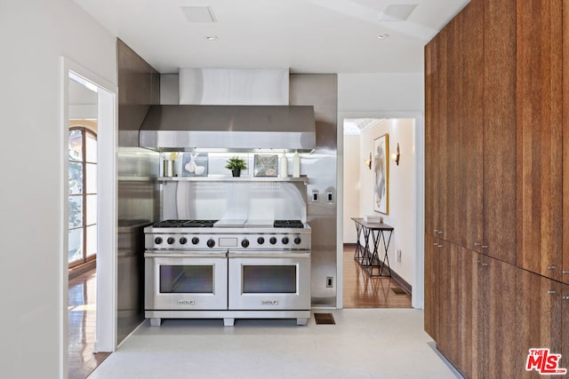 kitchen with double oven range and wall chimney range hood