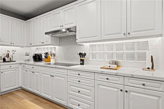 kitchen featuring tasteful backsplash, black electric stovetop, white cabinets, and light hardwood / wood-style flooring