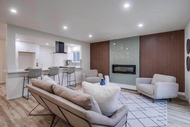 living room with a tiled fireplace and light hardwood / wood-style flooring