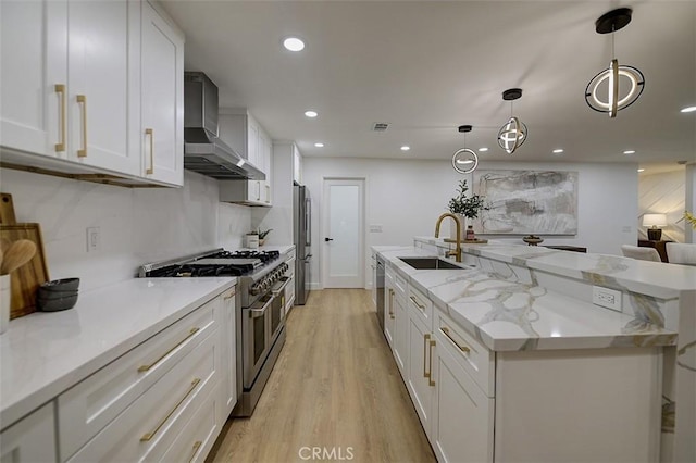 kitchen with stainless steel appliances, pendant lighting, white cabinetry, and wall chimney range hood