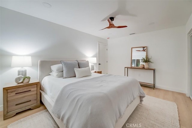 bedroom featuring ceiling fan, light wood finished floors, visible vents, and baseboards