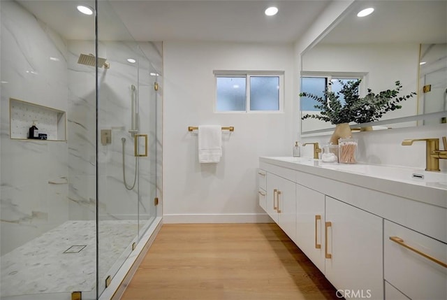 bathroom featuring hardwood / wood-style flooring, a shower with shower door, and vanity