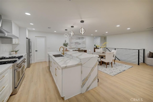 kitchen with stainless steel appliances, a kitchen island with sink, a sink, and white cabinetry