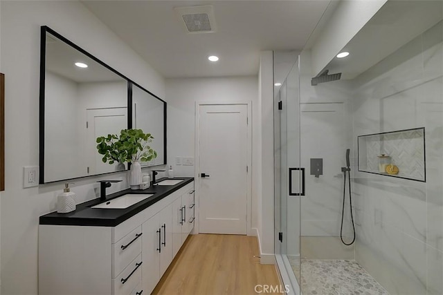 bathroom with a shower with shower door, hardwood / wood-style floors, and vanity