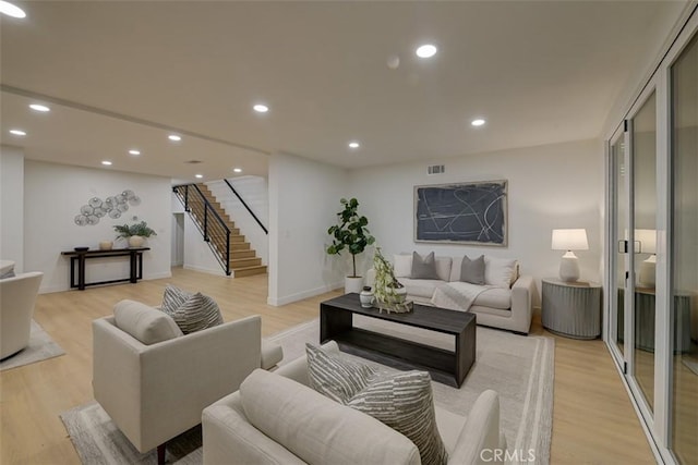 living room featuring light wood-type flooring, stairs, visible vents, and recessed lighting