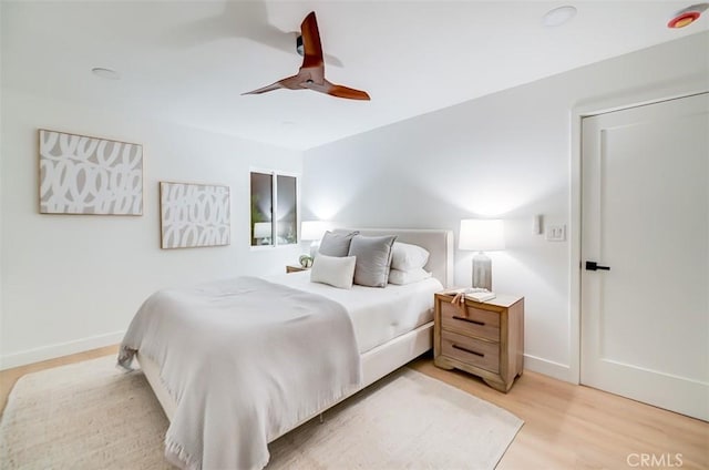 bedroom with a ceiling fan, light wood-style flooring, and baseboards