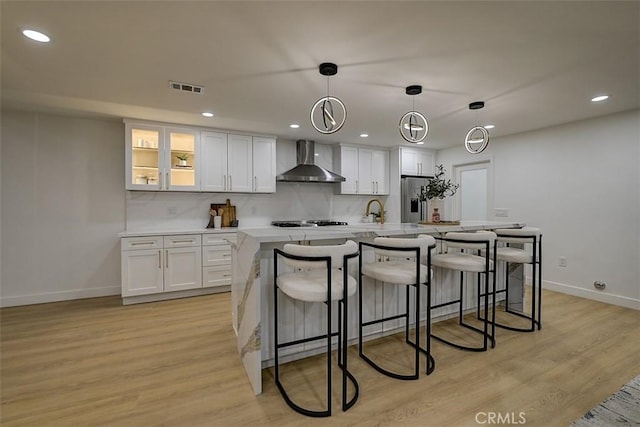 kitchen with wall chimney exhaust hood, light countertops, decorative light fixtures, and white cabinetry