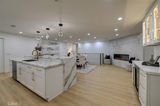 kitchen featuring white cabinetry, sink, a fireplace, and an island with sink