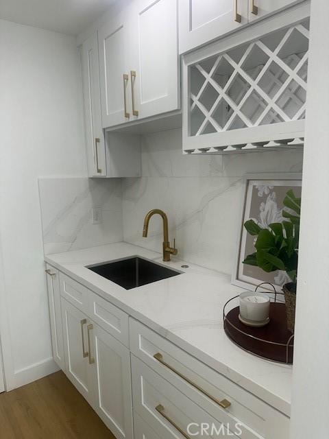 kitchen featuring backsplash, dark hardwood / wood-style flooring, sink, and white cabinetry