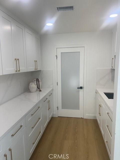 interior space featuring dark hardwood / wood-style floors, white cabinetry, tasteful backsplash, and light stone countertops