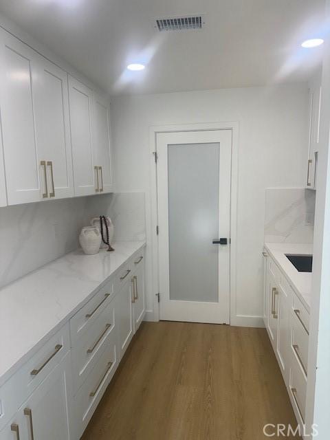 kitchen featuring dark wood-style floors, visible vents, white cabinetry, and light stone countertops