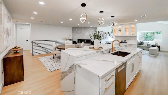 kitchen with decorative light fixtures, dishwasher, white cabinets, and sink