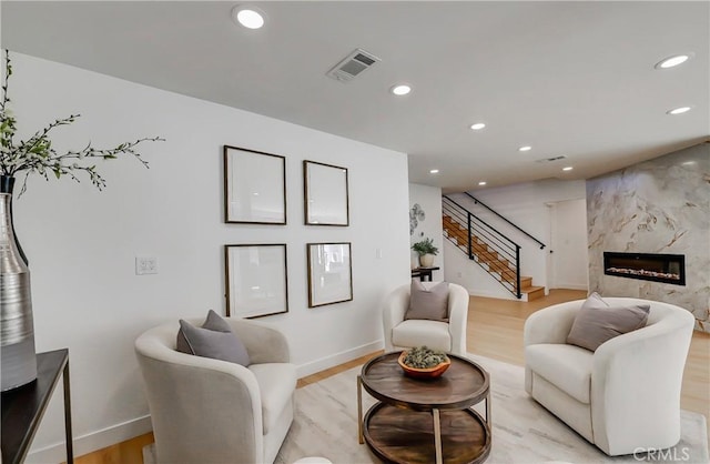 living room with a high end fireplace and light hardwood / wood-style floors