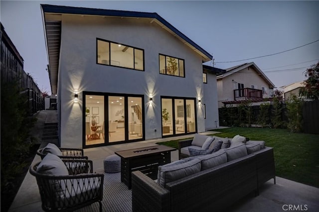 back house at dusk with an outdoor living space with a fire pit, a patio area, and a yard