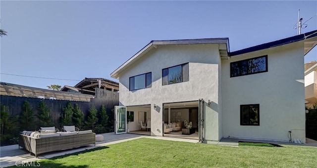 back of property with an outdoor living space, a lawn, and a patio