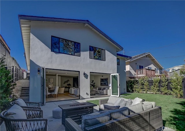 rear view of house featuring stucco siding, a yard, a fenced backyard, and an outdoor hangout area