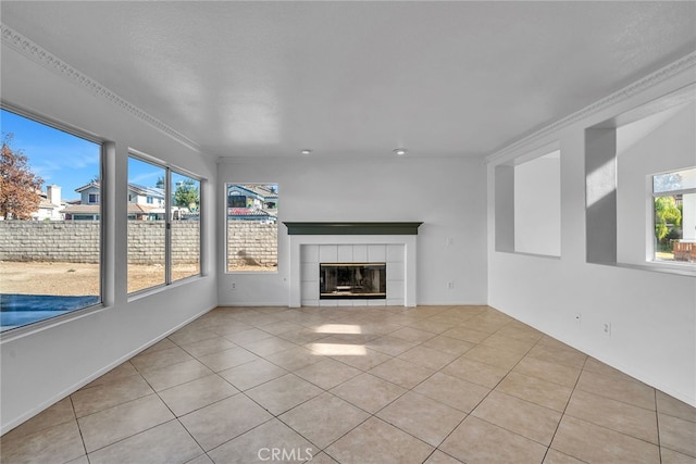 unfurnished living room featuring a wealth of natural light, light tile patterned floors, crown molding, and a tile fireplace