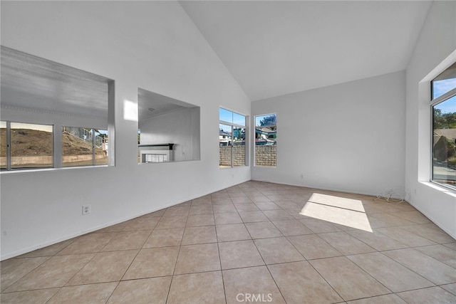 spare room with plenty of natural light, light tile patterned floors, and high vaulted ceiling