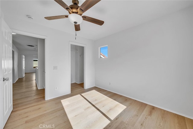 unfurnished bedroom featuring ceiling fan, a spacious closet, light hardwood / wood-style flooring, and a closet