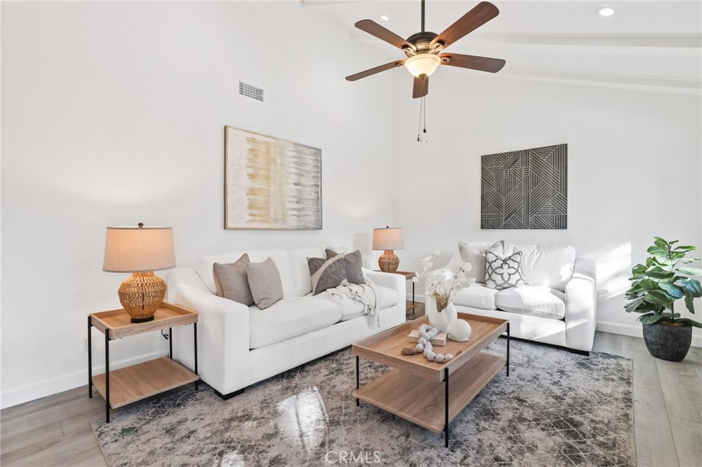 living room featuring vaulted ceiling with beams, ceiling fan, and wood-type flooring