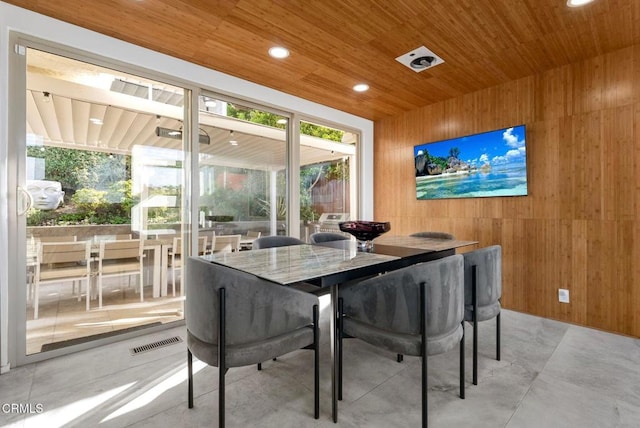 dining room featuring wooden ceiling and wood walls