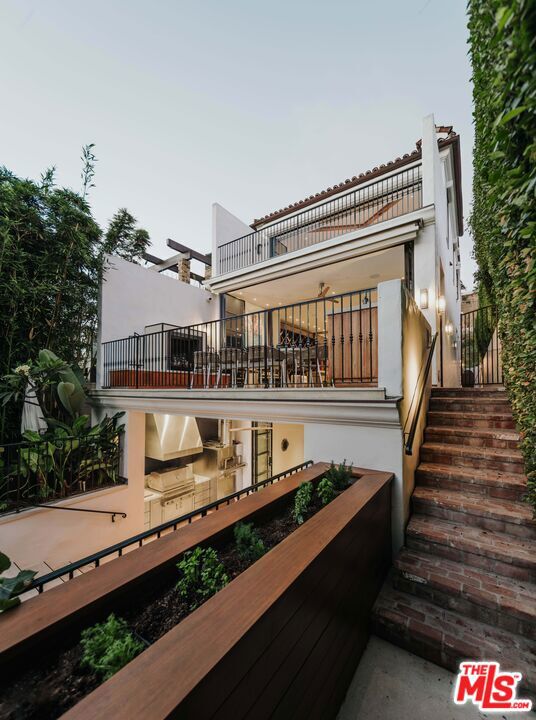 back house at dusk featuring a balcony and an outdoor kitchen