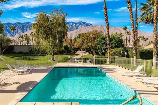 view of swimming pool featuring a mountain view, a yard, and a patio area