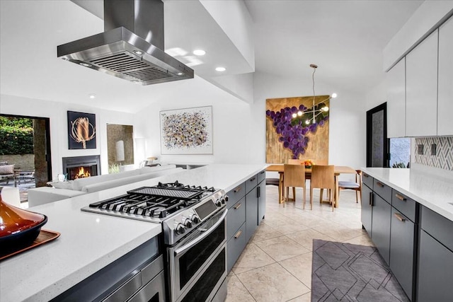 kitchen with pendant lighting, range with two ovens, vaulted ceiling, white cabinetry, and island exhaust hood