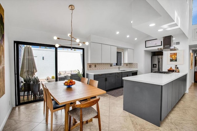 kitchen with hanging light fixtures, sink, gray cabinets, range hood, and stainless steel appliances