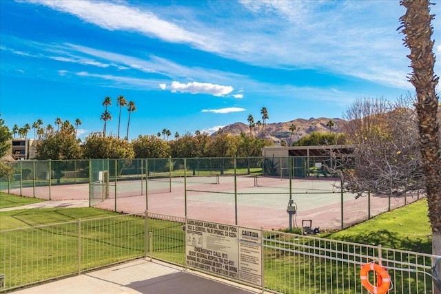 view of tennis court with a mountain view and a yard