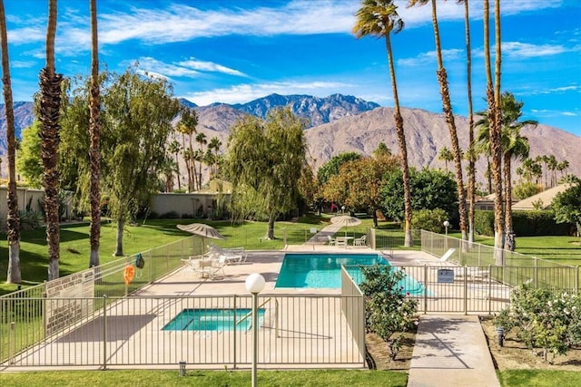 view of swimming pool featuring a lawn, a mountain view, a patio, and a hot tub