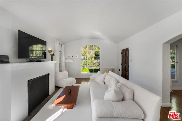 living room featuring dark hardwood / wood-style floors, vaulted ceiling, and brick ceiling