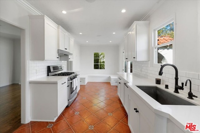 kitchen featuring gas stove, white cabinetry, sink, and tasteful backsplash