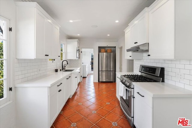 kitchen featuring backsplash, white cabinets, sink, dark tile patterned floors, and stainless steel appliances