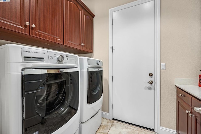 laundry area with washer and dryer, light tile patterned flooring, and cabinets