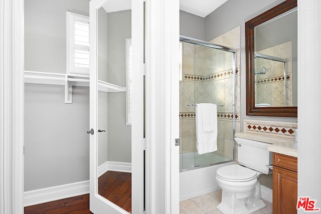 full bathroom with vanity, bath / shower combo with glass door, and toilet