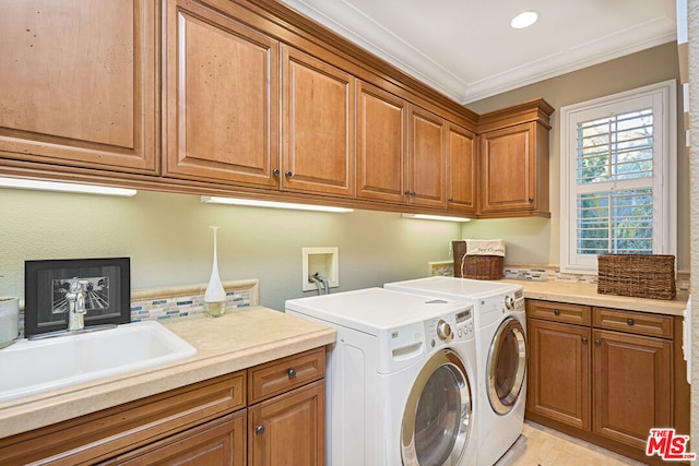 laundry area with cabinets, independent washer and dryer, ornamental molding, and sink