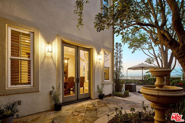 exterior entry at dusk with a patio and french doors