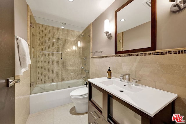 full bathroom featuring vanity, combined bath / shower with glass door, tile patterned flooring, toilet, and tile walls