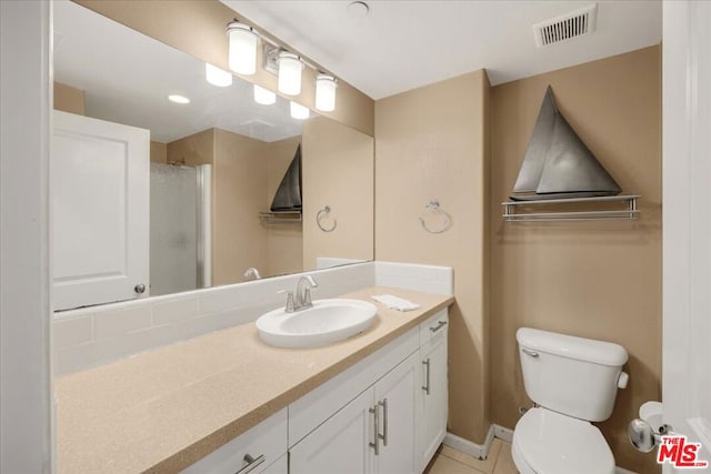 bathroom featuring tile patterned flooring, vanity, toilet, and a shower with shower door