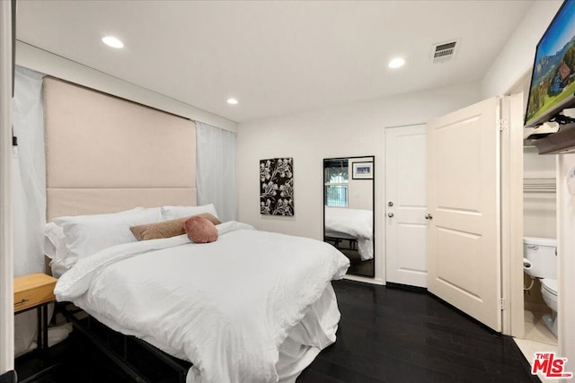 bedroom with ensuite bathroom and dark hardwood / wood-style floors