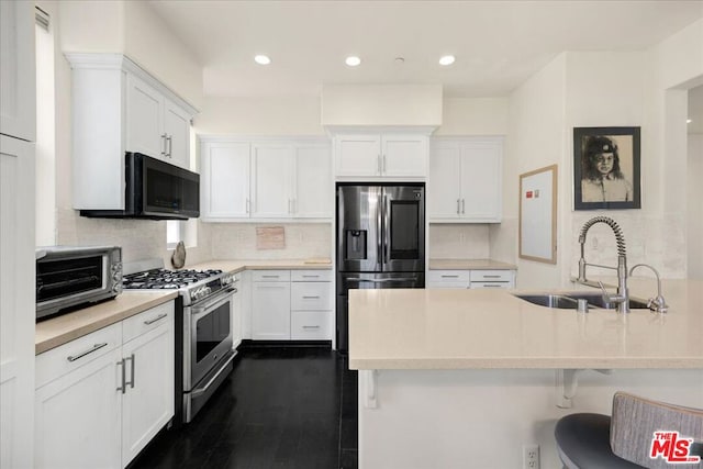 kitchen featuring appliances with stainless steel finishes, tasteful backsplash, sink, white cabinets, and a breakfast bar area